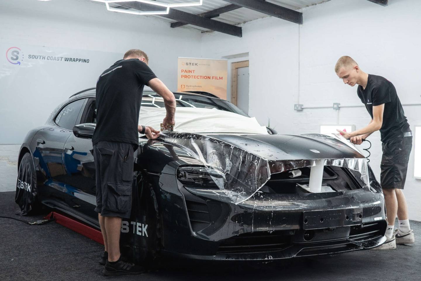 Two installers positioning protective film across a bonnet