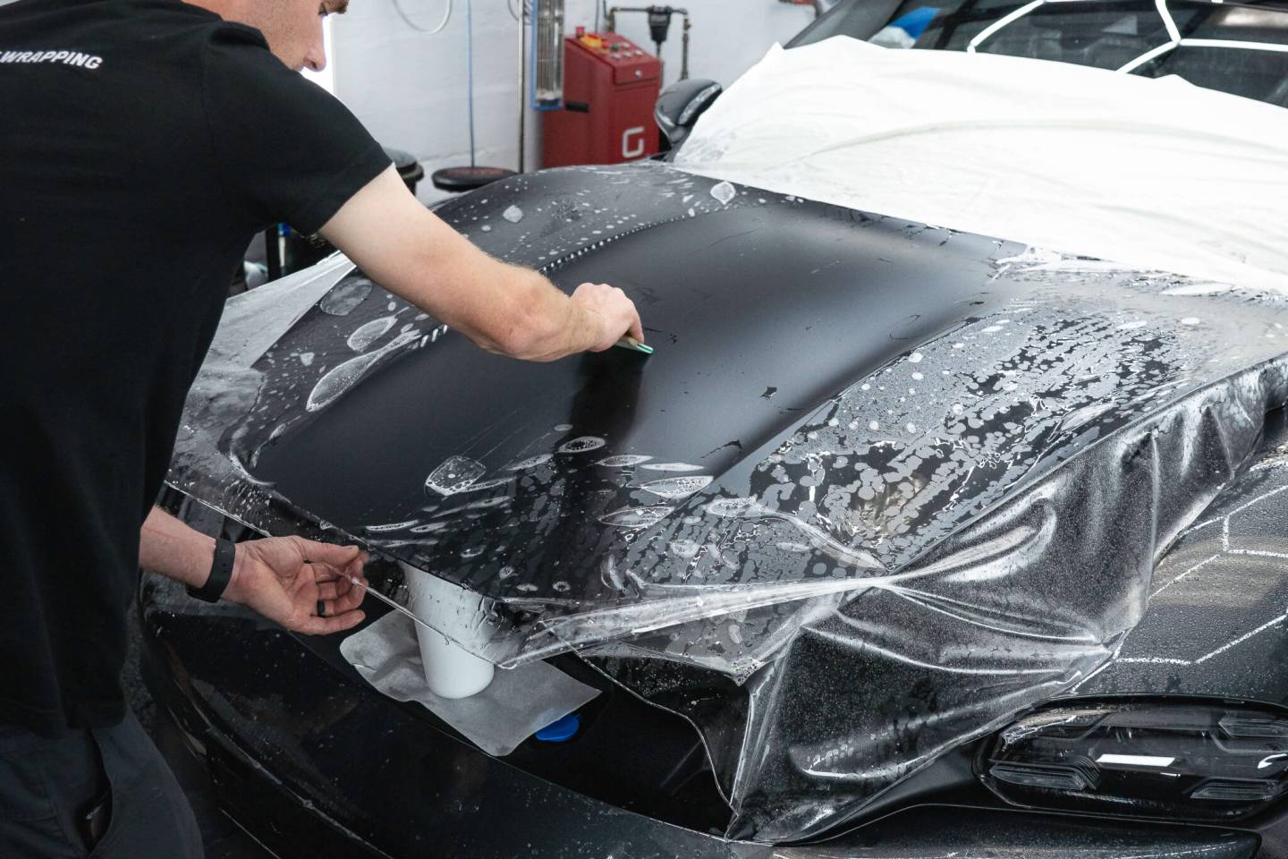 Installer smoothing protective film across a car bonnet