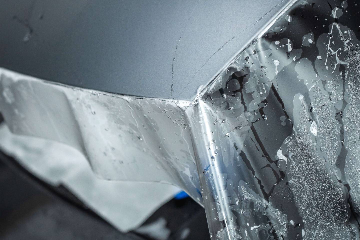 Paint protection film being fitted around a grey body panel edge