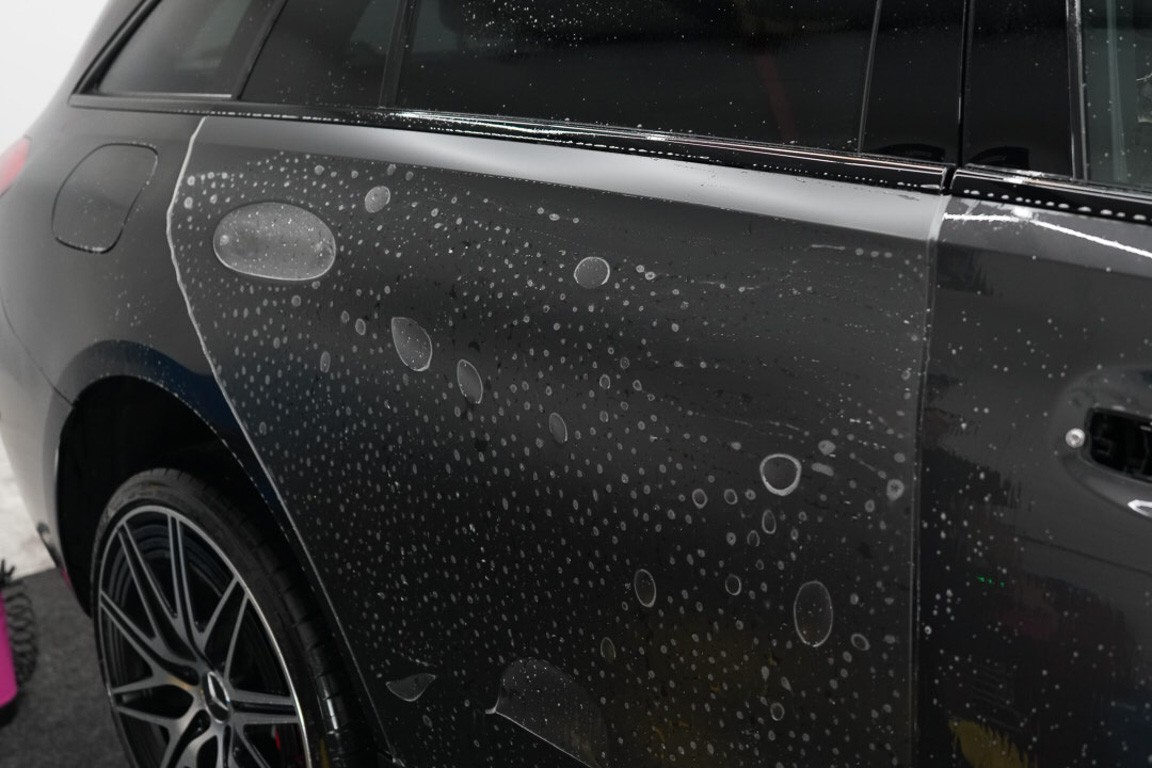 Side view of a grey vehicle during paint protection film installation