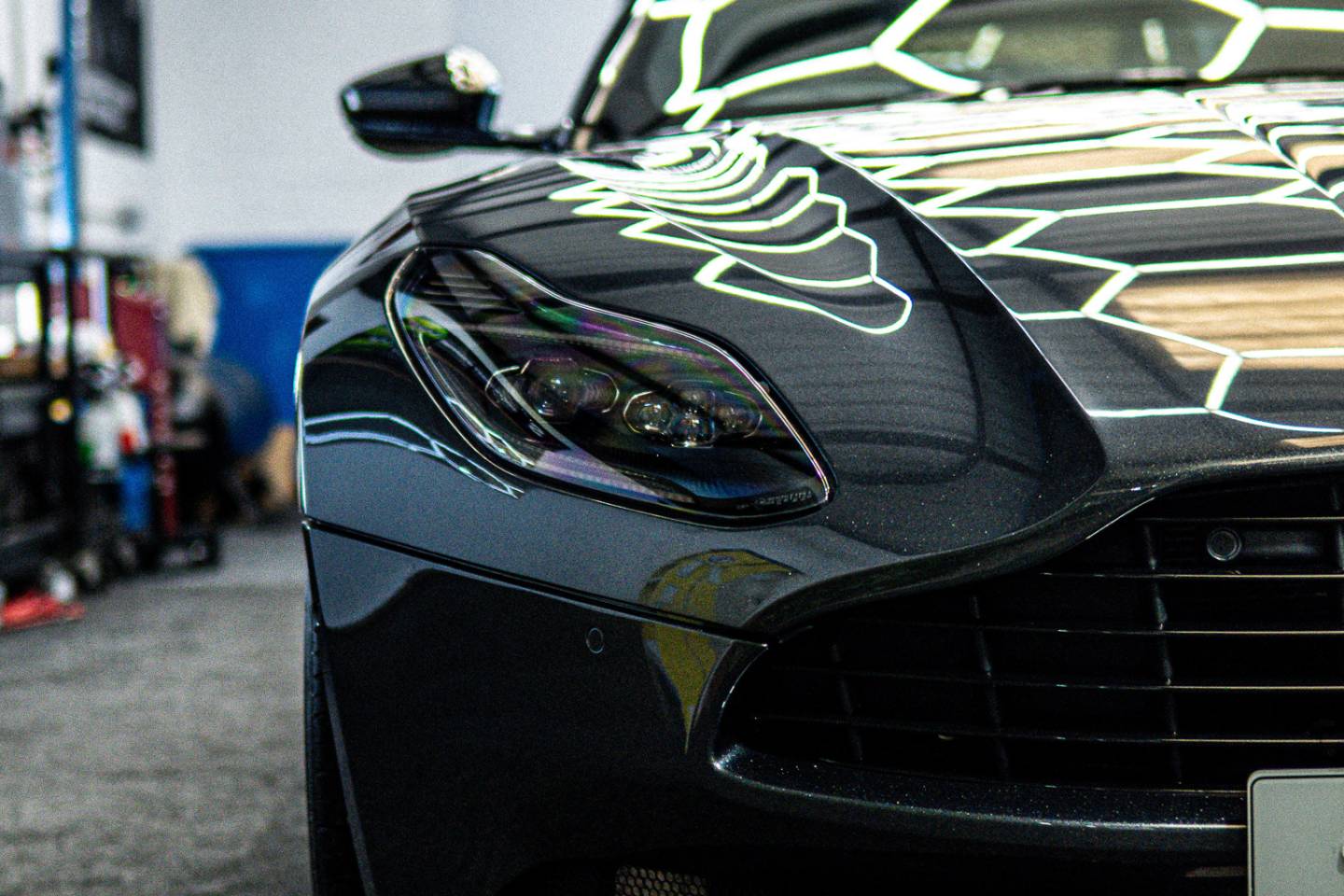 Grey Aston Martin bonnet reflecting workshop lights