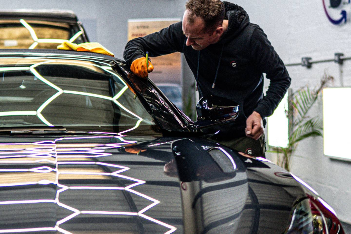 Installer working on the front of a grey Aston Martin