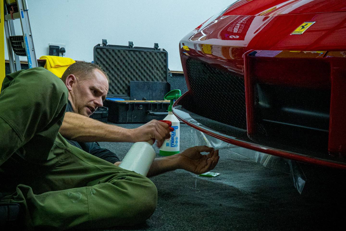 Installer working on a red Ferrari front bumper