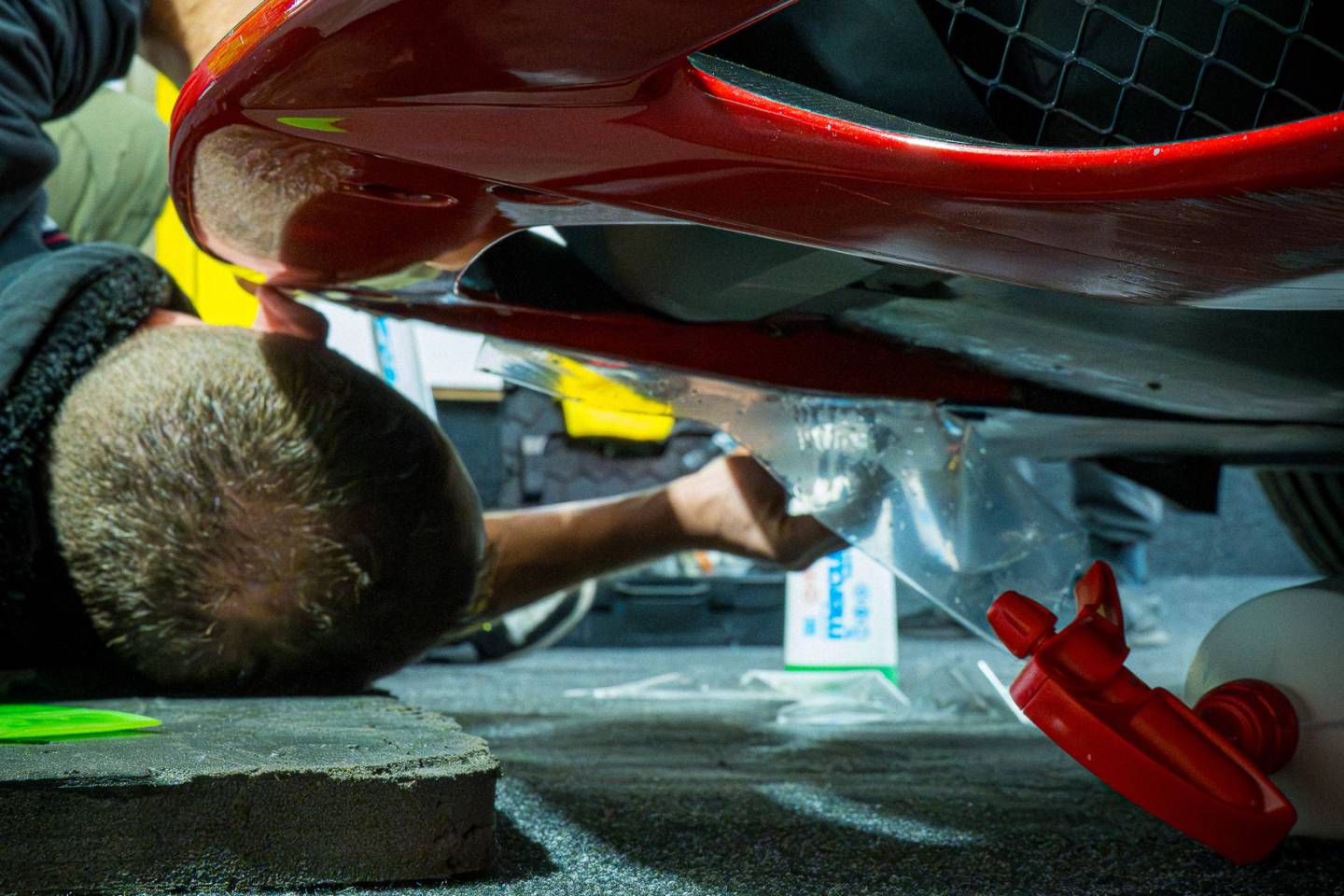 Underside of a red Ferrari front bumper during installation
