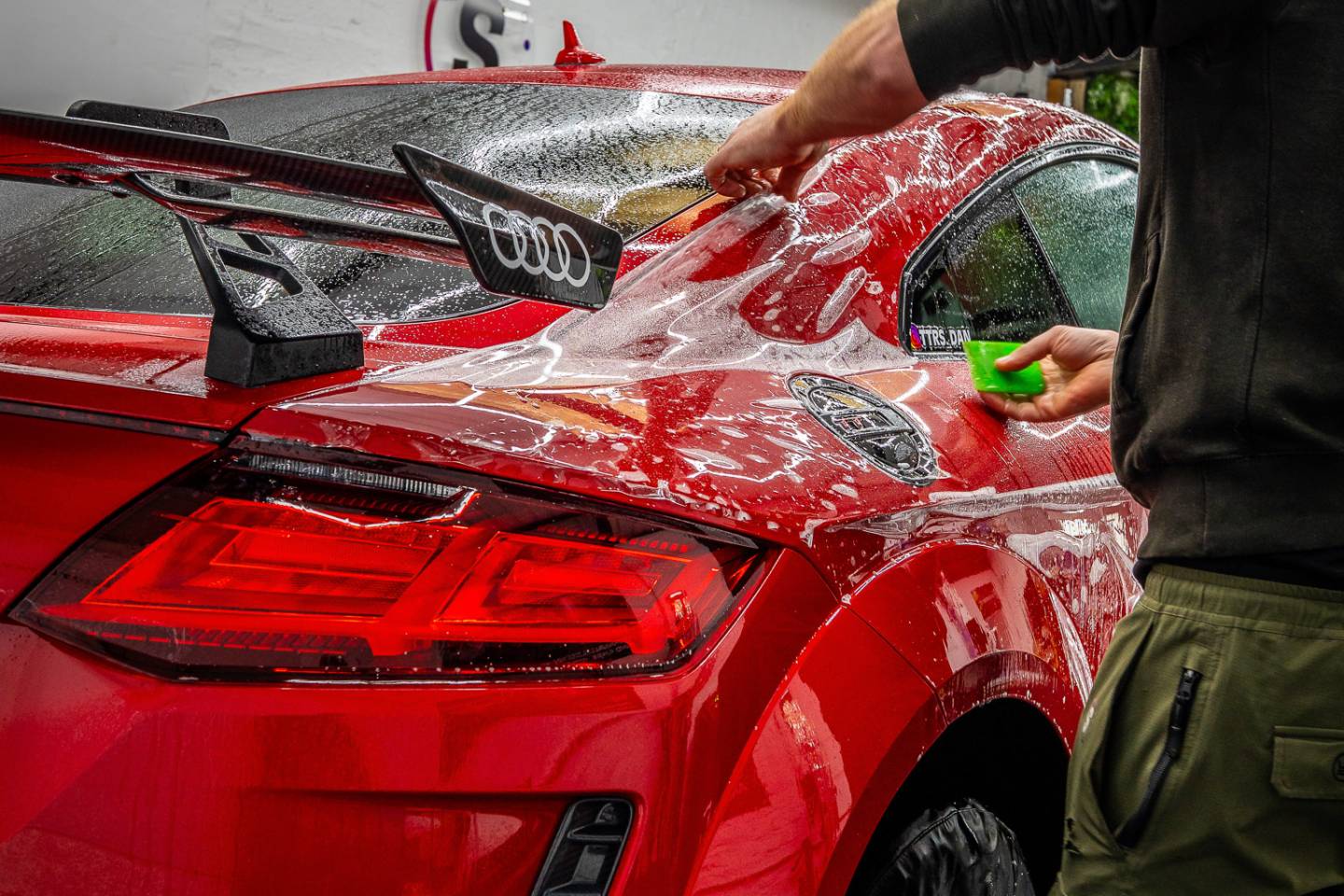 Clear protective film being fitted over red Ferrari bodywork