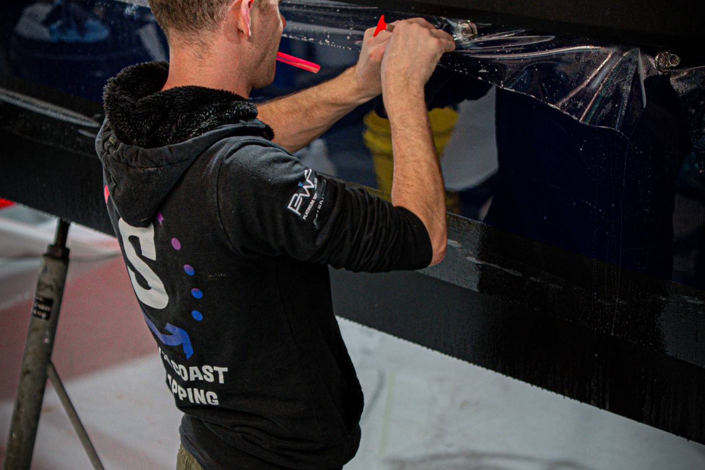 Installer fitting protective film to a blue body panel