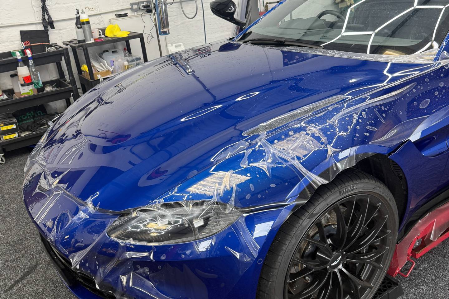 Blue sports car bonnet reflecting workshop lighting