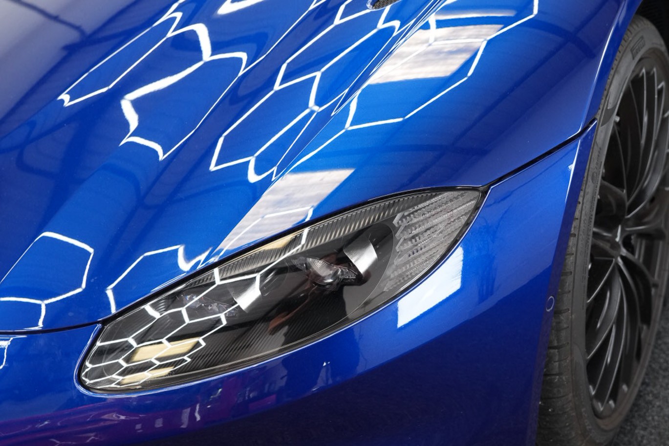 Blue sports car bonnet reflecting workshop lights