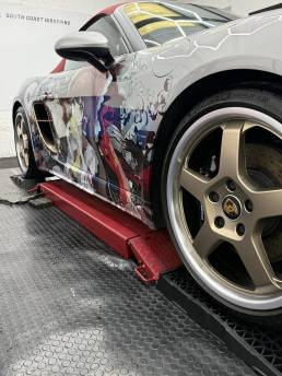 Anime artwork and gold rear wheel on Porsche convertible