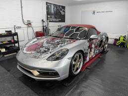 Silver Porsche convertible with custom anime wrap in the workshop