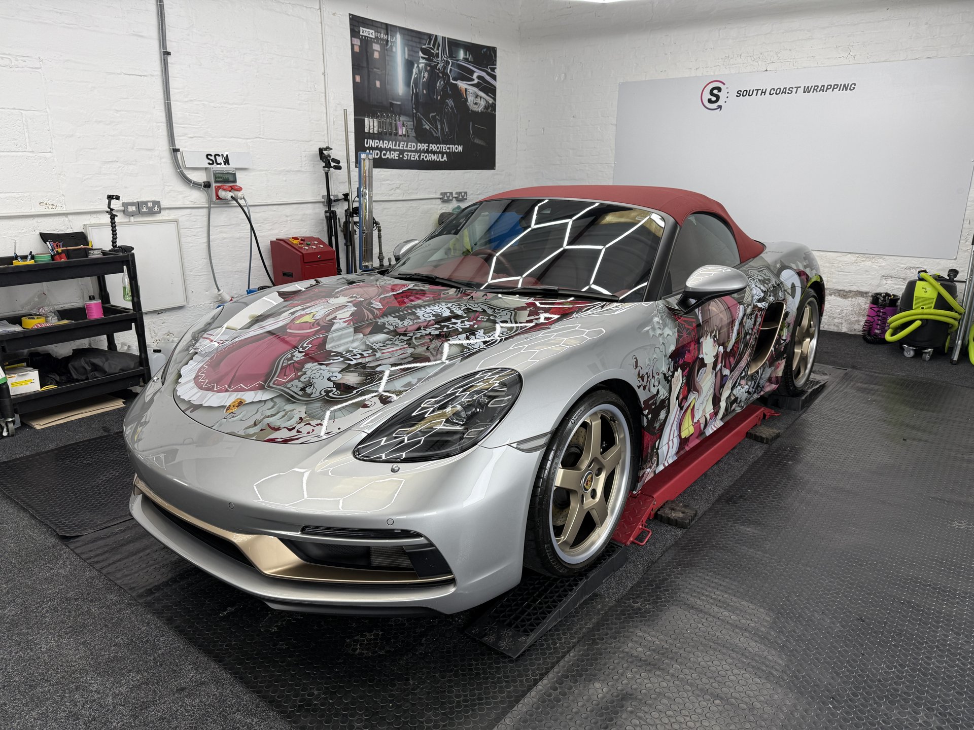 Silver Porsche convertible with custom anime wrap in the workshop