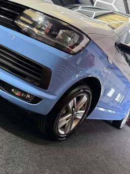 Front three-quarter view of blue and white VW Transporter