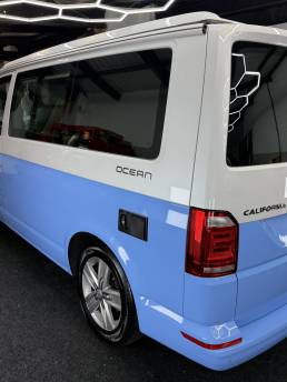 Rear three-quarter view of blue and white VW Transporter