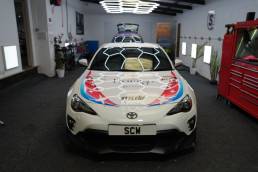 Front view of white Toyota GT86 with anime graphics
