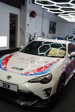Front three-quarter view of anime-wrapped Toyota GT86
