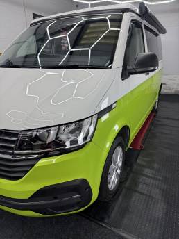 Front three-quarter view of lime green and white VW Transporter