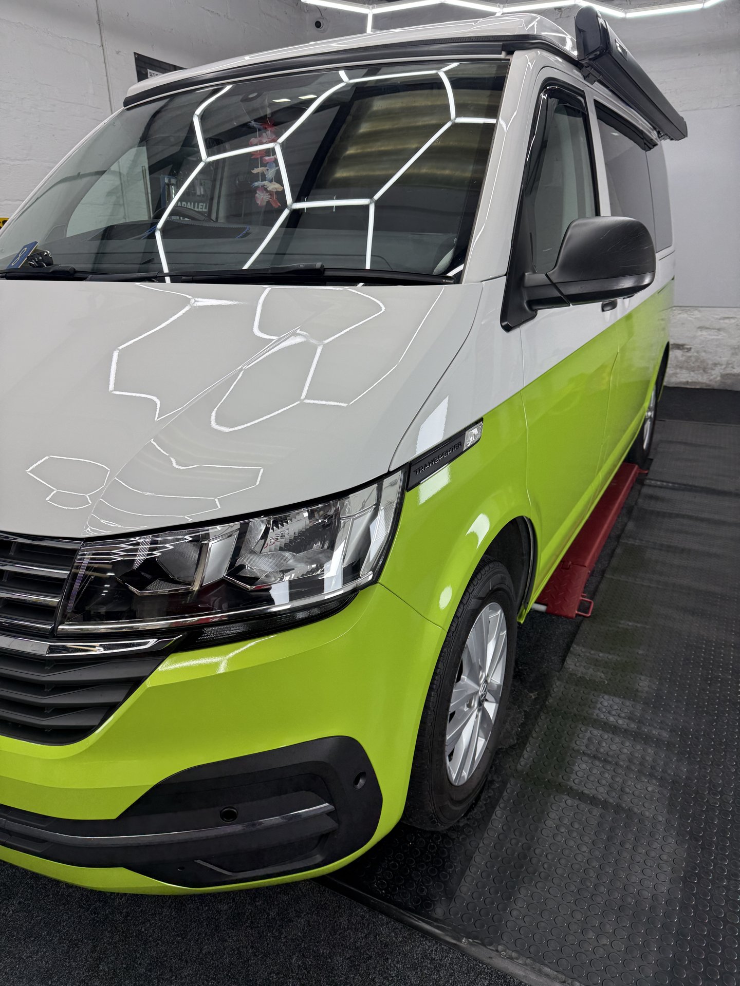 Front three-quarter view of lime green and white VW Transporter